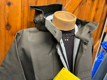 Load image into Gallery viewer, Green waterproof coat on a mannequin with the hood up showing the interior lining, placed against a wooden background.